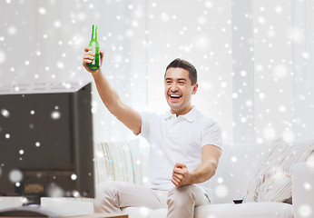 Image showing smiling man watching tv and drinking beer at home