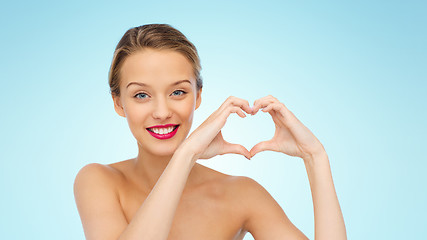 Image showing smiling young woman showing heart shape hand sign