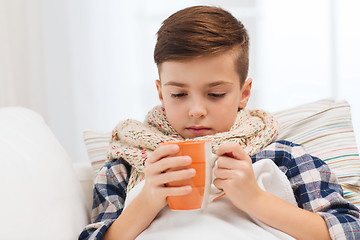 Image showing ill boy with flu in scarf drinking tea at home