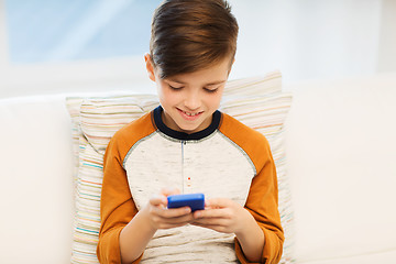 Image showing boy with smartphone texting or playing at home