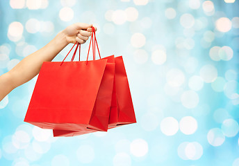 Image showing close up of hand holding red shopping bags