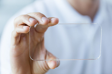 Image showing close up of male hand with transparent smartphone