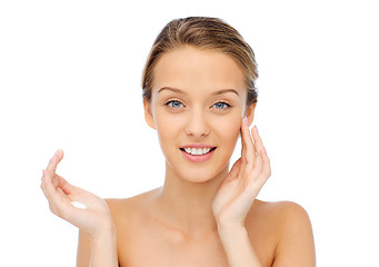 Image showing happy young woman applying cream to her face