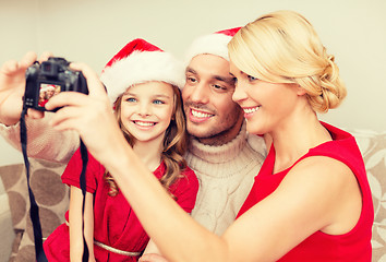 Image showing smiling family in santa helper hats taking picture