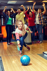 Image showing happy young woman throwing ball in bowling club