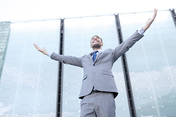 Image showing young smiling businessman over office building