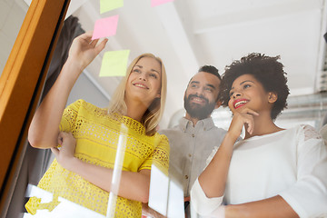 Image showing happy creative team writing on stickers at office