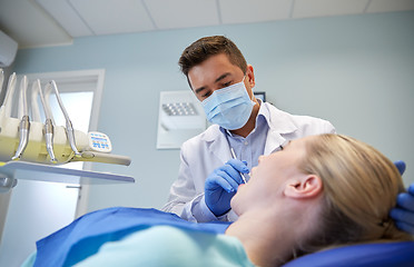 Image showing male dentist in mask checking female patient teeth