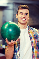 Image showing happy young man holding ball in bowling club