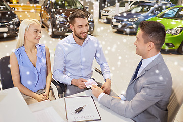 Image showing happy couple with car dealer in auto show or salon