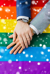 Image showing close up of male gay couple hands on rainbow flag