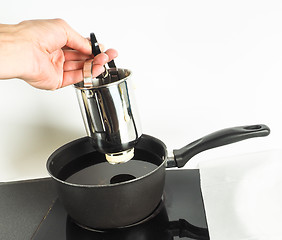 Image showing Baker making donuts with a squeeze container into hot oil in sma