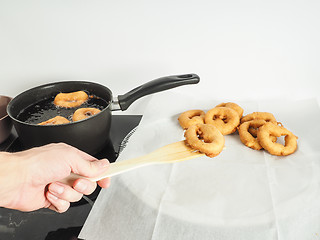 Image showing Hand of person lifting freshly made donut from bolier to paper