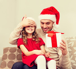 Image showing smiling father surprises daughter with gift box