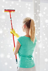 Image showing happy woman in gloves cleaning window with sponge