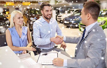 Image showing happy couple with car dealer in auto show or salon