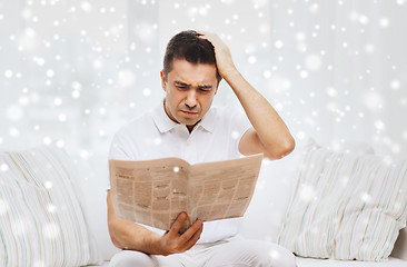 Image showing sad man reading newspaper at home