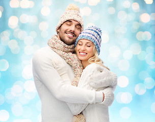 Image showing happy couple in winter clothes hugging over lights