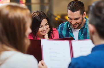 Image showing smiling couple with friends and menu at restaurant