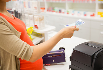 Image showing pregnant woman with money at cashbox in drugstore