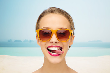 Image showing happy young woman in sunglasses showing tongue