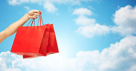 Image showing close up of hand holding red shopping bags