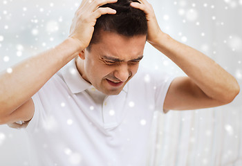 Image showing unhappy man suffering from head ache at home