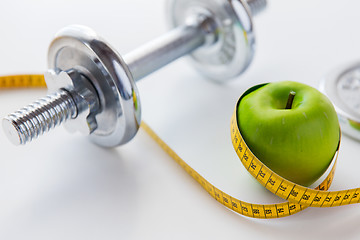 Image showing close up of dumbbell and apple with measuring tape