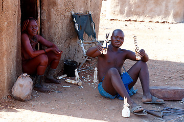 Image showing Himba man adjusts wooden souvenirs