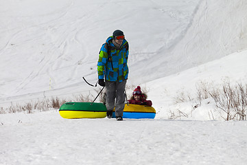 Image showing Father and daughter with snow tube