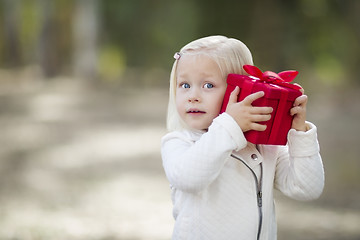 Image showing Baby Girl Holding Red Christmas Gift Outdoors