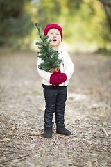 Image showing Baby Girl In Red Mittens and Cap Holding Small Christmas Tree