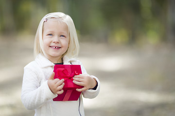 Image showing Baby Girl Holding Red Christmas Gift Outdoors