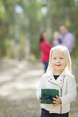 Image showing Baby Girl With Christmas Gift Outdoors Parents Behind