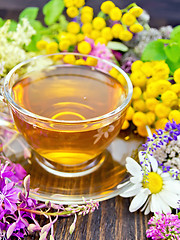 Image showing Tea from wild flowers in glass cup on board