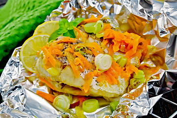 Image showing Pike with carrots and leeks in foil on dark board