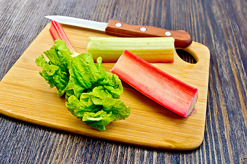Image showing Rhubarb with knife and leaf on dark board