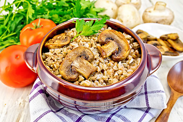 Image showing Buckwheat with champignons in clay bowl on towel