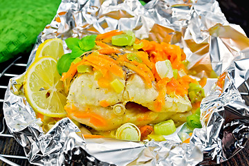 Image showing Pike with carrots and leeks in foil on board