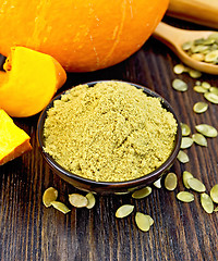 Image showing Flour pumpkin in bowl with seeds and spoon on board