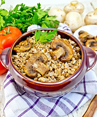 Image showing Buckwheat with champignons in clay bowl on light board