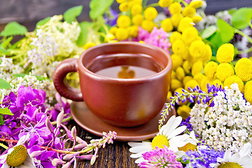 Image showing Tea from flowers in clay cup on dark board