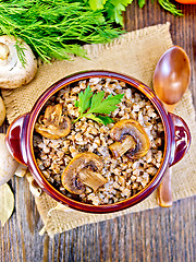 Image showing Buckwheat with champignons in clay bowl on table top