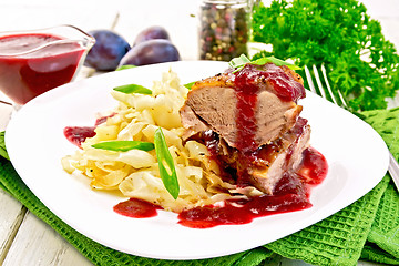 Image showing Duck breast whole with plum sauce and cabbage in plate on napkin