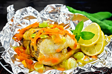 Image showing Pike with carrots and onions in foil on dark board