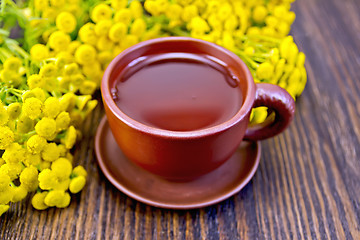 Image showing Tea from tansy in clay cup on board