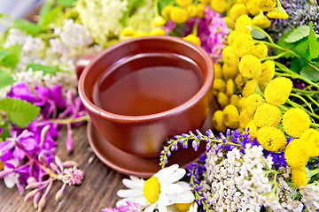 Image showing Tea from wild flowers in clay cup on board