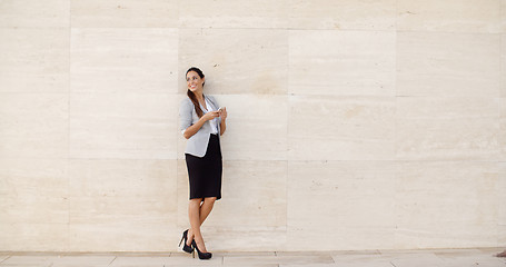 Image showing Stylish businesswoman standing against a wall