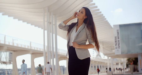 Image showing Stylish woman with long hair standing on a mobile