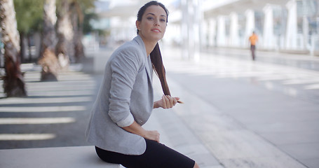 Image showing Pretty woman sitting beside a pedestrian walkway